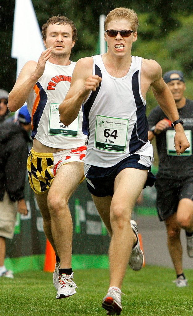 Fryeburg Academy graduate Silas Eastman, right, and Nate Hathaway of Scarborough run through the rain toward the finish line in Fort Williams.