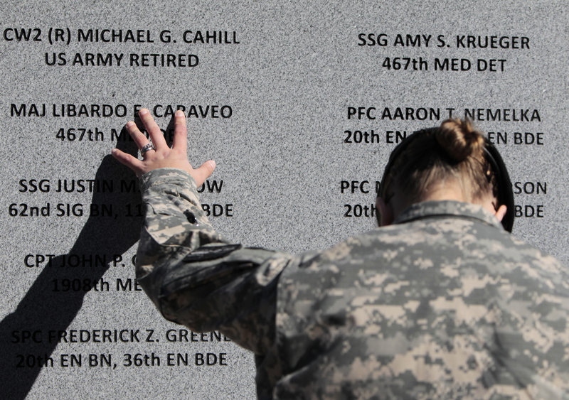 Staff Sgt. Joy Clark runs her fingers over the engraved names of soldiers, victims of the worst mass shooting in history on a U.S. military base, during a November 2010 ceremony marking the one-year anniversary of the Fort Hood rampage.