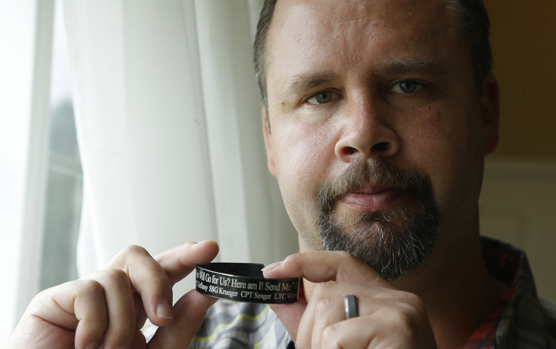 Retired Army Staff Sgt. Shawn Manning holds a memorial bracelet for members of his military unit who were killed in the 2009 mass shooting. Manning still carries two bullets in his body from the attack.
