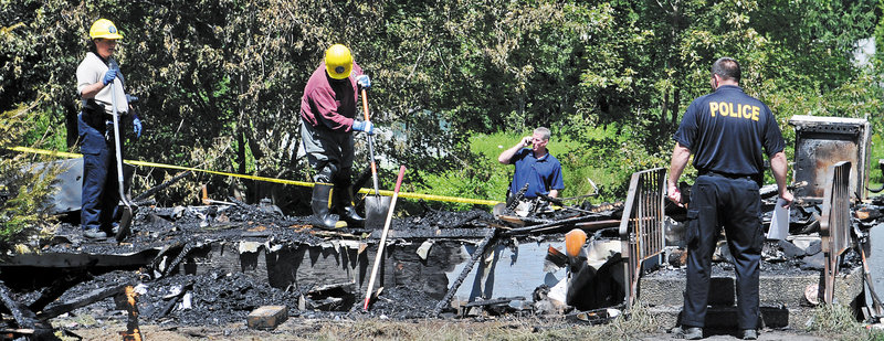 Investigators from the Office of the State Fire Marshal and Richmond Police examine the remnants of a mobile home that burned Sunday night on Kimball Street in Richmond.
