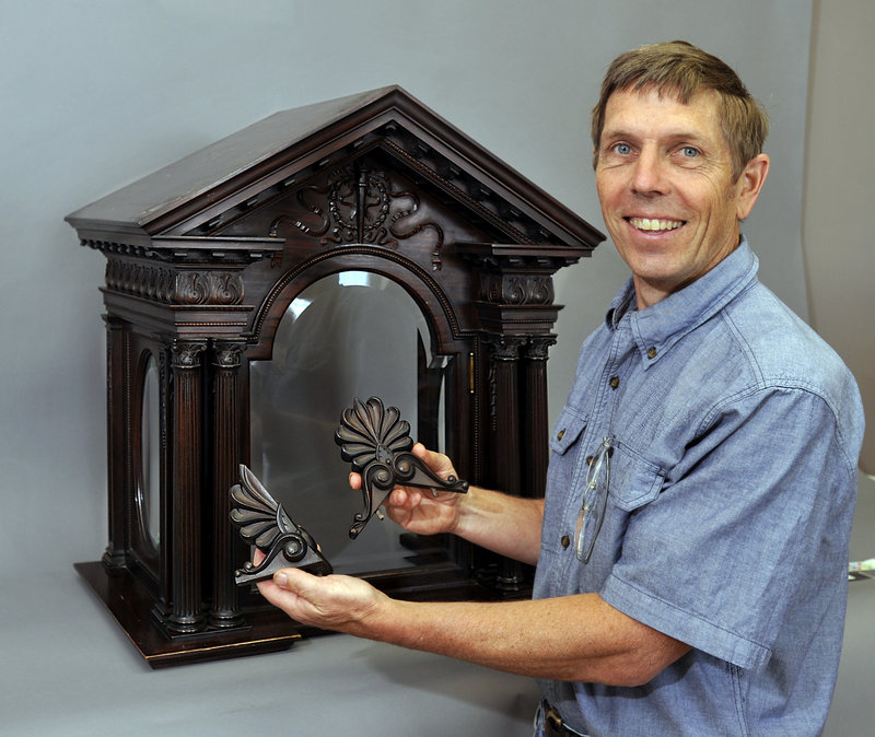 Jon Brandon shows two pieces of an 1898 clock bonnett to be repaired by his company.