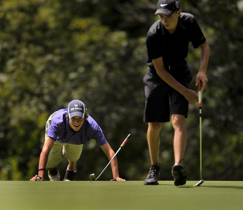 Will Kannegieser of Minot gets as low as possible Wednesday to study a putt as Drew Powell of Bangor marks his ball during the Maine Junior golf tournament.