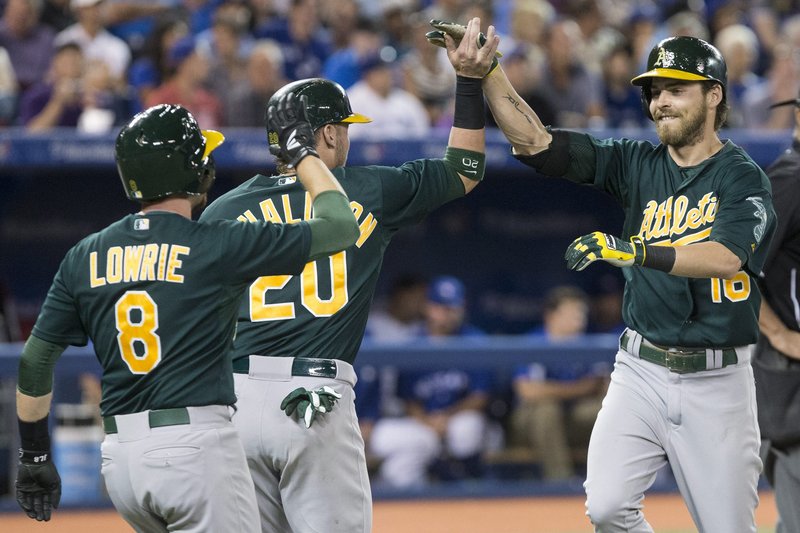 Josh Reddick of the A’s is greeted by Josh Donaldson and Jed Lowrie after hitting his third home run of the game Friday in a 14-6 win over the Blue Jays at Toronto.