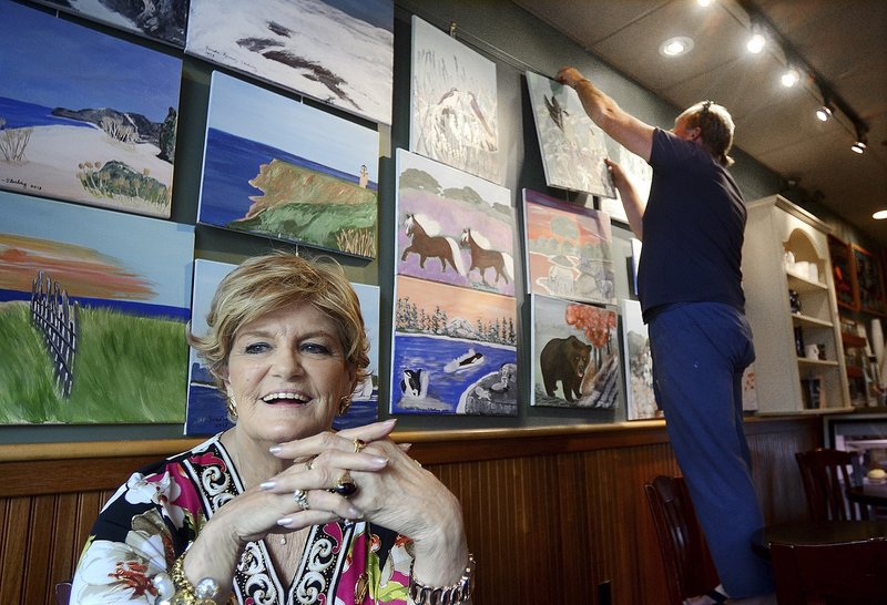 Artist Sandra Ramsey-Sterling, 76, of Haverhill, Mass., smiles while her paintings are arranged at the Lone Gull Cafe, in Gloucester, Mass., June 16. Ramsey-Sterling, who has been a beauty-pageant success, business owner and a wife and mother, has found satisfaction in recent years as a painter.