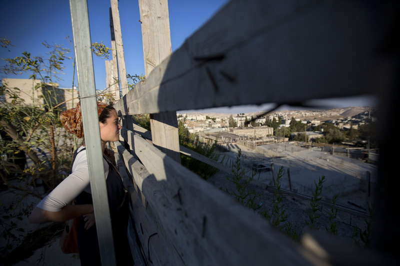An Israeli woman looks at a construction site during a ceremony Sunday to mark the resumption of building new housing units in an east Jerusalem neighborhood.