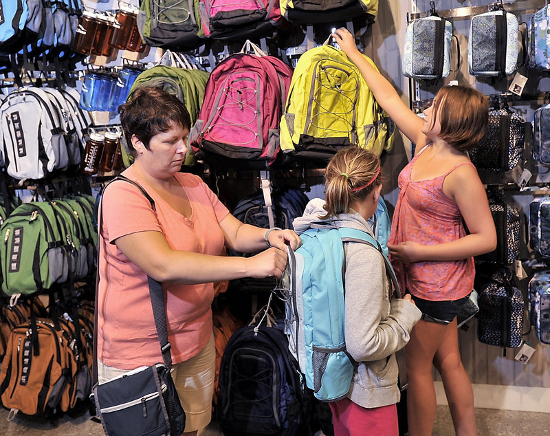 Leanne MacKay helps her daughters, Maggie, 13, and Emily, 11, choose backpacks at the L.L. Bean store in Freeport on Tuesday. The family, from Halifax, Nova Scotia, said they are combining their vacation time with back-to-school shopping for clothes and supplies.