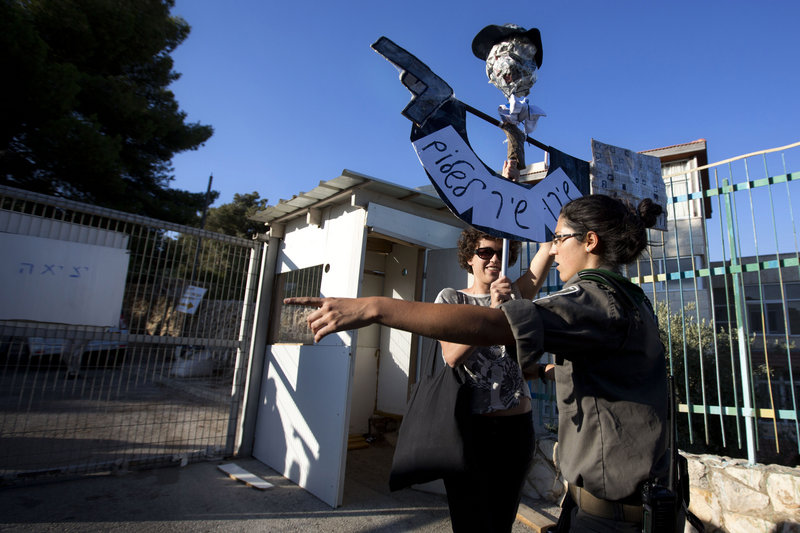 An Israeli border police officer argues with a left-wing Israeli activist protesting the resumption of housing construction in east Jerusalem on Sunday. Ahead of Israeli-Palestinian peace talks beginning Wednesday, Israel announced that it is planning for more than 3,000 new homes for Jews in the West Bank and east Jerusalem, areas the Palestinians want for a state.