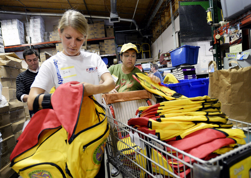 Dez Dearborn, left, and Angelea Errington-Cyr, both Unum employees, grab backpacks to hand out to other Unum employees who volunteered to stuff backpacks for students in need Wednesday, August 14, 2013. The event took place at Ruth's Reusable Resources, which spearheaded another year of helping needy schoolchildren start the school year right.