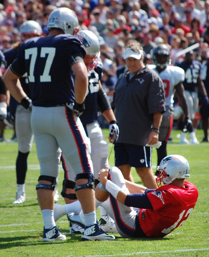 Tom Brady grabs his left knee after being knocked down during a joint workout with the Tampa Bay Buccaneers on Wednesday in Foxborough, Mass. It’s the same knee Brady hurt in the 2008 opener.