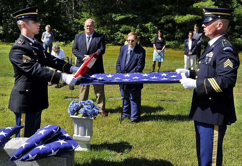 As family look on, Sgt. Casey Lawrence, left, and Sgt. David Chabe, fold the flag during a special ceremonial service in Hiram for four servicemen with the Lyons and Gray families killed in past wars.