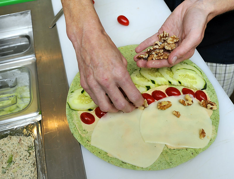 Jeannie Dunnigan, owner of Cia Cafe in South Portland, makes a veggie roll-up with fresh local produce.