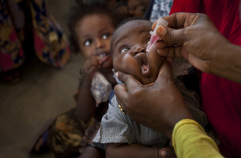 A health care worker gives polio vaccine to a young child. An outbreak of the disease is occurring in Somalia.