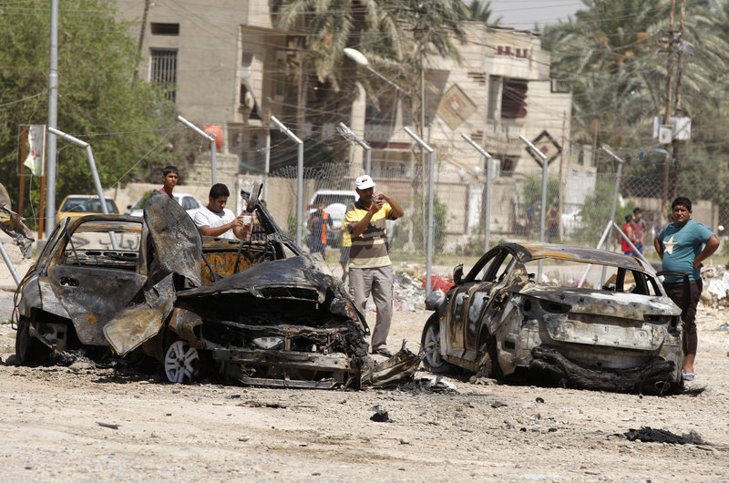 Civilians look at the aftermath of a car bomb attack in Baghdad on Thursday. More than 3,000 people have been killed in violence during the past few months, leading Iraq to ask the United States for assistance stopping the violence, which is tied to al-Qaeda.