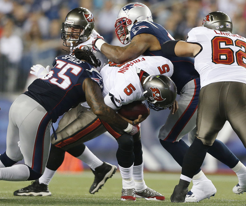 New England middle linebacker Brandon Spikes, left, and defensive tackle Tommy Kelly sack Tampa Bay Buccaneers quarterback Josh Freeman during the first quarter.