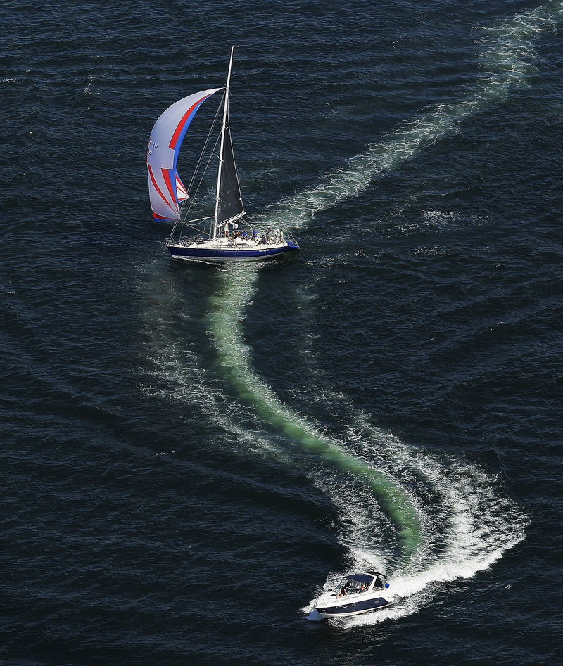 A sailboat crosses the wake of a powerboat during the regatta.
