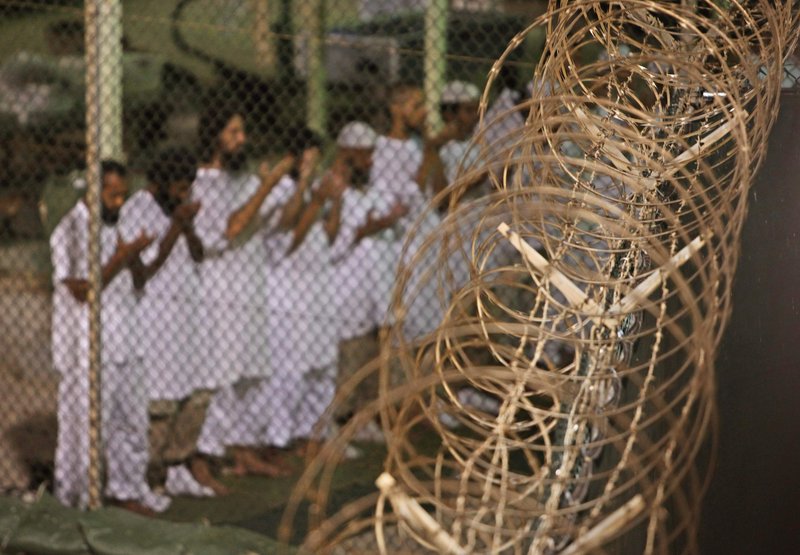 Guantanamo detainees pray before dawn near a fence of razor-wire at the prison on the U.S. naval base in Cuba. The prison once held as many as 680 men but now has 166 prisoners as the government figures out how to close the facility.