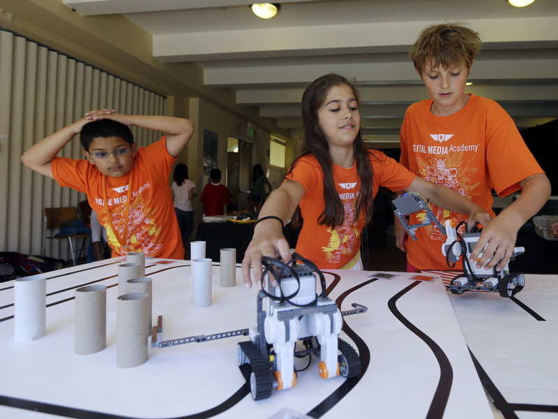 Saci Marty, center, and Callum Brown, right, put their robotic Lego Mindstorms units through an obstacle course during a Digital Media Academy workshop, in Stanford, Calif.