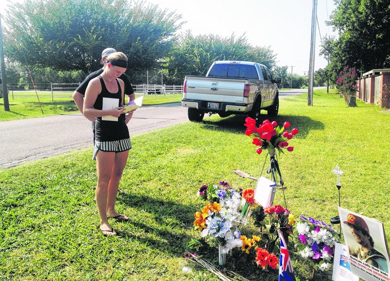 Sarah Harper, Christopher Lane's girlfriend, stands beside a memorial along the road where Lane, and Australian baseball player, was shot to death Friday in Duncan, Okla.