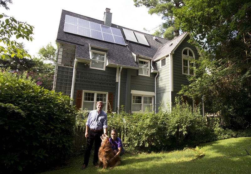 Ketch Ryan, right, and her neighbor Kirk Renaud pose next her solar-paneled house in Chevy Chase, Md.