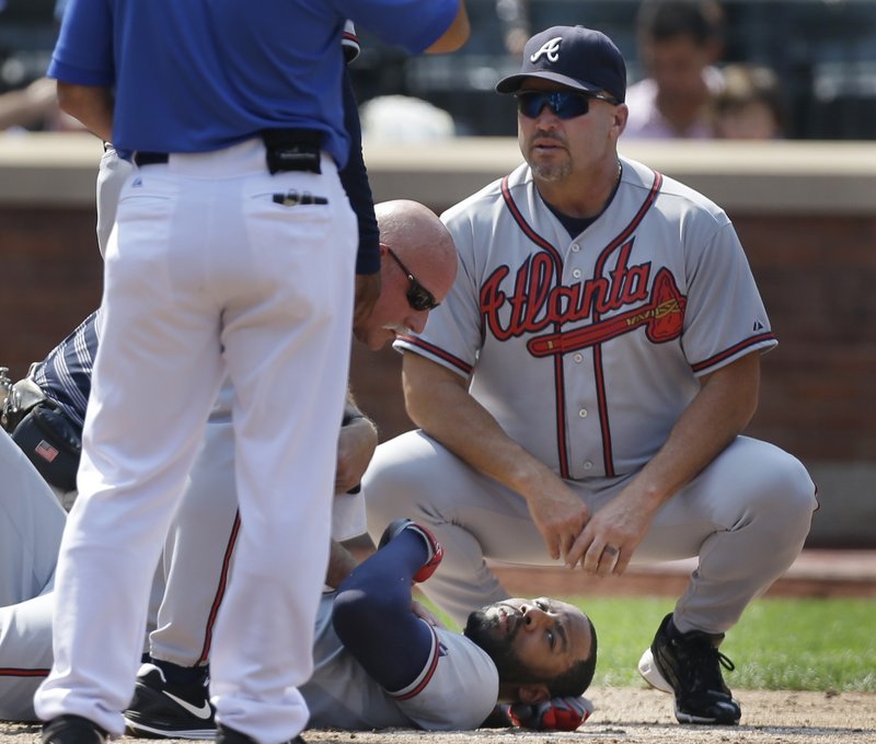 Atlanta’s Jason Heyward lies on the ground while Manager Fredi Gonzalez crouches nearby after Heyward was hit in the face by a pitch Wednesday against the Mets.