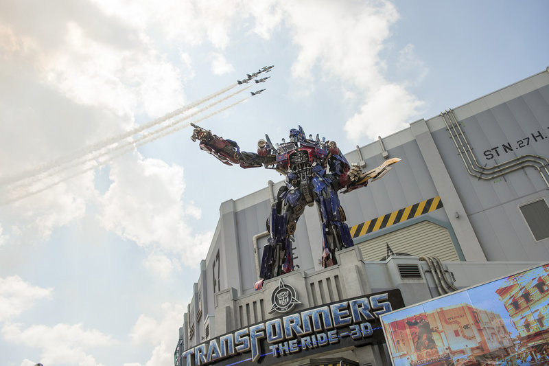 A three-story Optimus Prime figure towers at the entrance to the Transformers: The Ride-3D as a formation of private jets flies overhead at the attraction’s grand opening June 20 at the Universal Orlando Resort in Orlando, Fla.