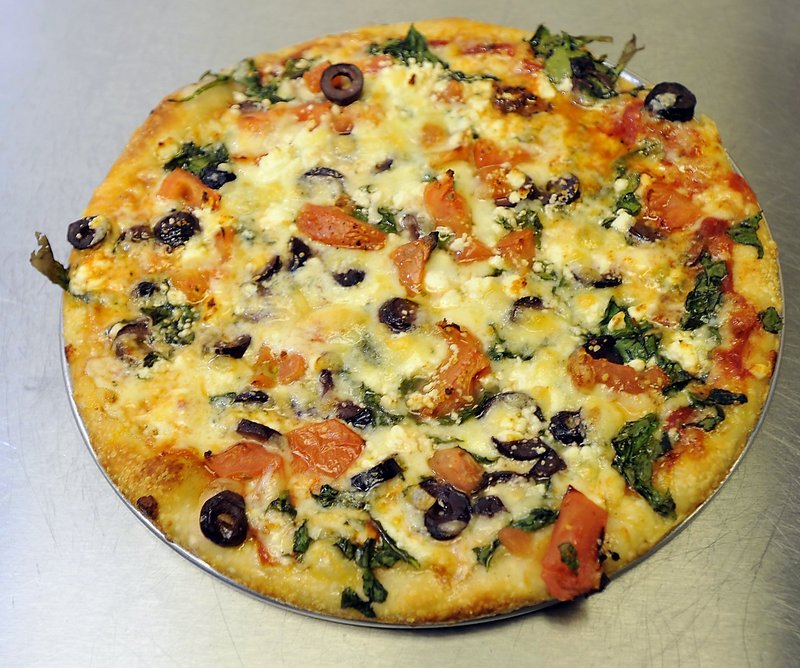 A Greek pizza with spinach, tomato, feta and Greek olives.