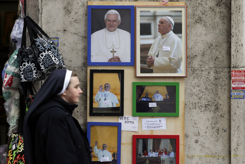 A nun walks past pictures of newly elected Pope Francis and one of Pope Emeritus Benedict XVI, top left, near the Vatican on March 15. Francis says he wants to shed the image of the Catholic Church as chauvinistic.