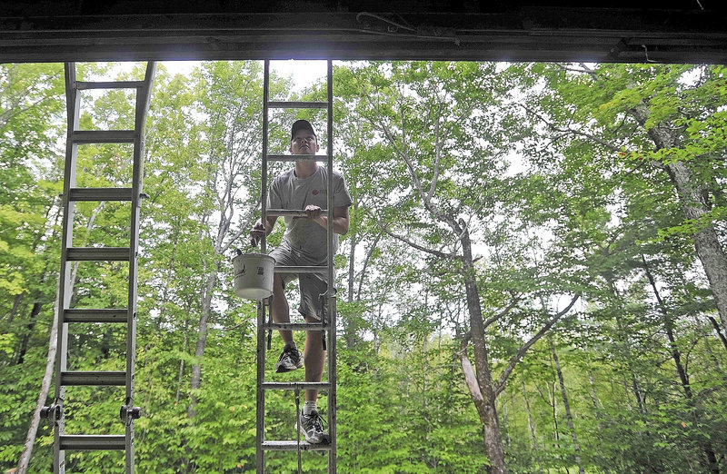 Mat Gross, of North New Portland, an employee with Backyard Farms, climbs the ladder to apply a fresh coat of paint on the Margaret Chase Smith Hall at Lake George Regional Park on the Canaan and Skowhegan town line Friday.