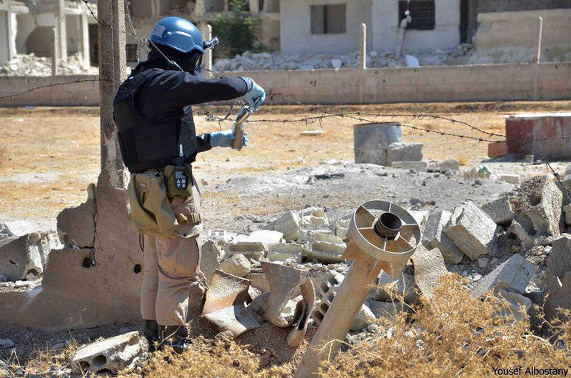 A member of a U.N. investigation team takes samples of sands near part of a missile considered likely to be one of the chemical rockets fired in the Damascus countryside of Ain Terma, Syria, on Wednesday.