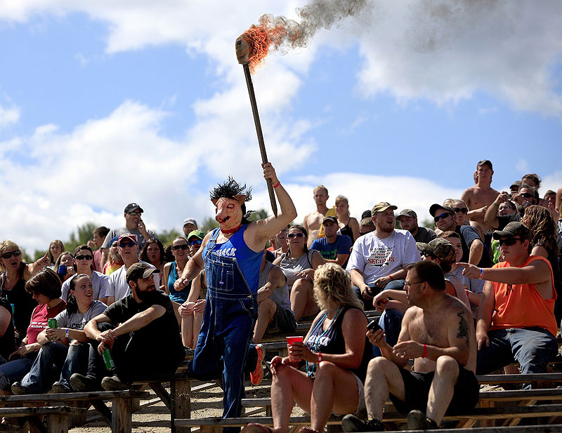 Leslie Strought carries the “Olympic torch” into the pit in Hebron on Saturday to start the Redneck (Blank) Games. The three-day extravaganza celebrates the redneck lifestyle, one that embodies self-reliance, simplicity and the outdoors.