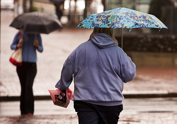Two umbrella-carrying pedestrians make their way through the rain along Congress Street in Portland on Monday, September 2, 2013.