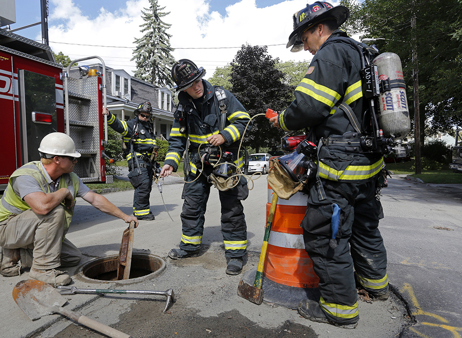 Portland firefighters Mike Scherb, right, and Travis Gibson test a manhole after a gas line break on Front Street in Portland. Photographed on September 5, 2013.