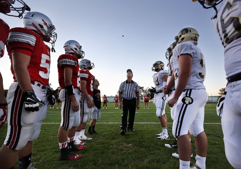 Captains from South Portland and Thorton Academy watch as referee Bob Webb tosses the coin to decide first possession on Friday, September 6, 2013.