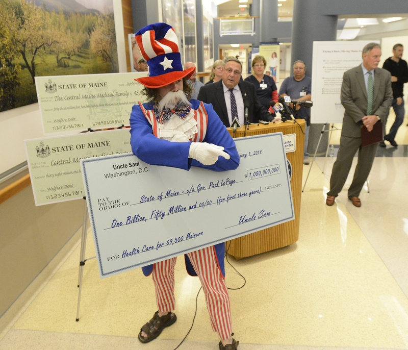 Gov. Paul LePage is interrupted by protester Paul Nickerson, dressed as Uncle Sam, during a news conference as LePage presents Central Maine Medical Center in Lewiston with a check for $38 million Wednesday.