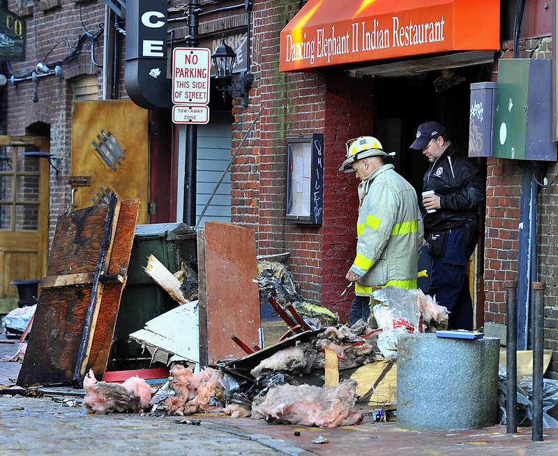 Portland Deputy Fire Chief David Jackson and a Portland health inspector survey damage from an early-morning fire Thursday in a Wharf Street building that damaged five businesses, including the Dancing Elephant II Indian restaurant.