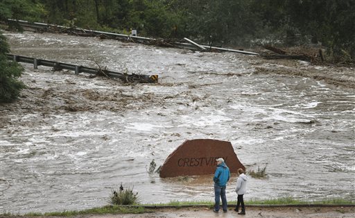 Local residents look over a road washed out by a torrent of water following overnight flash flooding near Left Hand Canyon, south of Lyons, Colo., on Thursday.