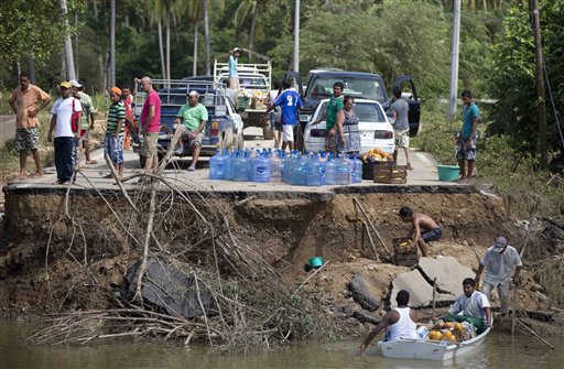 People stand on the edge of a collapsed bridge as they wait to ferry their goods via a boat across the Papagayos River, south of Acapulco, near Lomas de Chapultepec, Mexico, on Wednesday.
