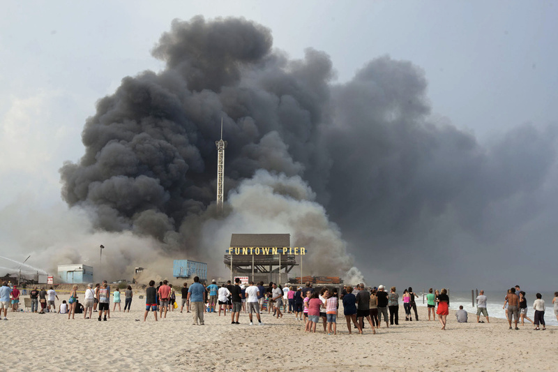 Onlookers watch from the shore as black smoke rises from a fire on the Seaside Heights, N.J., boardwalk. The fire started in the vicinity of an ice cream shop and burned several blocks of boardwalk and businesses in a town that was still rebuilding from damage caused by superstorm Sandy.