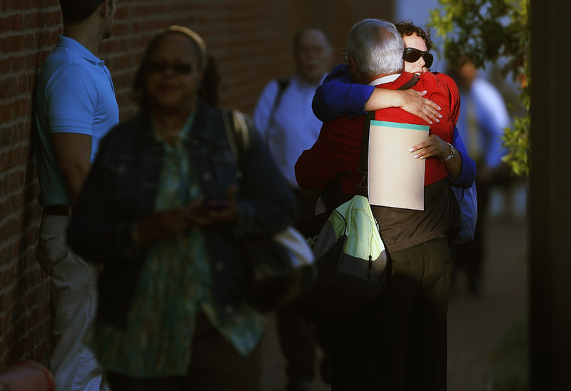 A woman hugs a man before entering the Washington Navy Yard as employees return to work Thursday. The Washington Navy Yard returned to nearly normal operations three days after it was the scene of a mass shooting in which a gunman killed 12 people.