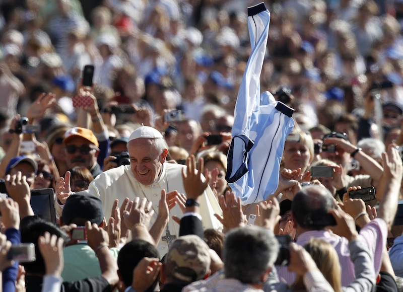 A faithful tosses in the air a jersey with the colors of the Argentine flag as Pope Francis greets faithful upon arrival for his weekly general audience in St. Peter's Square at the Vatican, Wednesday, Sept. 18, 2013. (AP Photo/Riccardo De Luca)