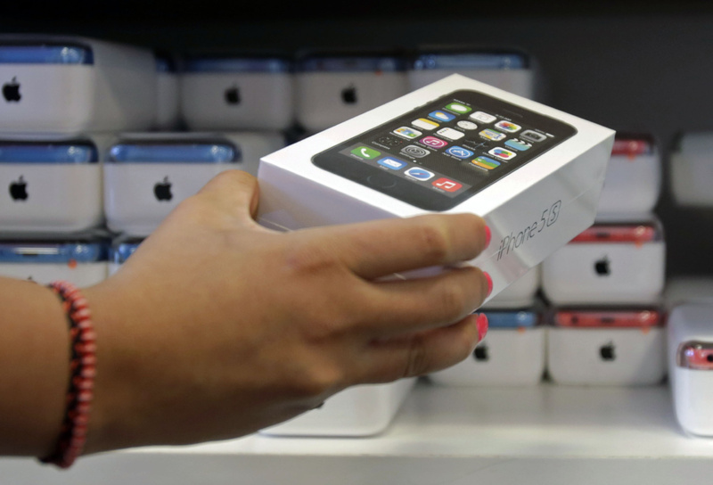 A sales clerk pulls out an iPhone 5s for a customer during the opening day of sales of the iPhone 5s and iPhone 5C, in Hialeah, Fla., on Friday.