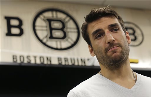 Boston Bruins center Patrice Bergeron talks with reporters in the team locker room, Tuesday, July 2, 2013, in Boston. The Bruins opened training camp Wednesday with only two roster spots seemingly uncertain, and those were on the third and fourth lines. (AP Photo/Charles Krupa)