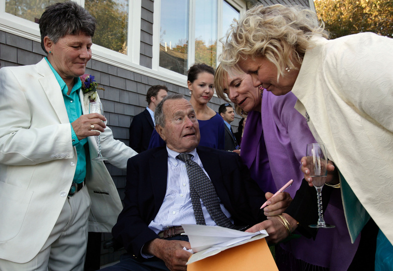 Former President George H.W. Bush prepares to sign the marriage license of longtime friends Helen Thorgalsen, right, and Bonnie Clement, left, in Kennebunkport, as officiant Nancy Sosa, third right, and Helen's daughter Lindsey, rear, look on in this May 22, 2014, photo. Bush was an official witness at the same-sex wedding, his spokesman said.