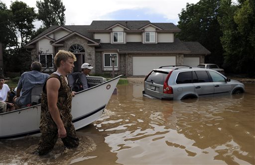 Eric and Pat Machmuller lead a boat down a residential street Saturday to help residents gather pets and belongings from their flooded homes in Longmont, Colo.