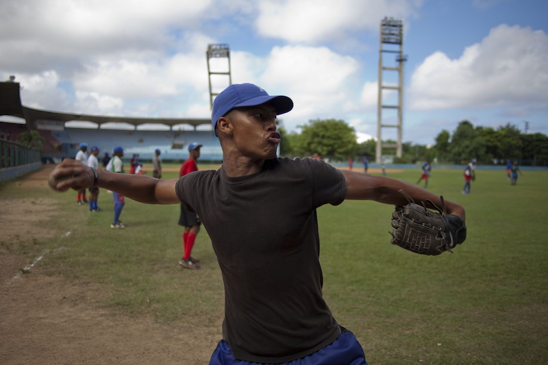 A baseball player who plays for the Cuban baseball team Industriales, winds up to throw a ball during a training session in Havana, Cuba, Friday, Sept. 27, 2013. Cuba announced Friday that its athletes will be allowed to sign contracts to compete in foreign leagues, a shift from decades of policy that held professional sports to be anathema to socialist ideals. The measure promises to increase the amount of money baseball players and others are able to earn, and seems geared toward stemming a continuing wave of defections by athletes who are lured abroad by the possibility of lucrative contracts, sapping talent from national squads. (AP Photo/Ramon Espinosa)