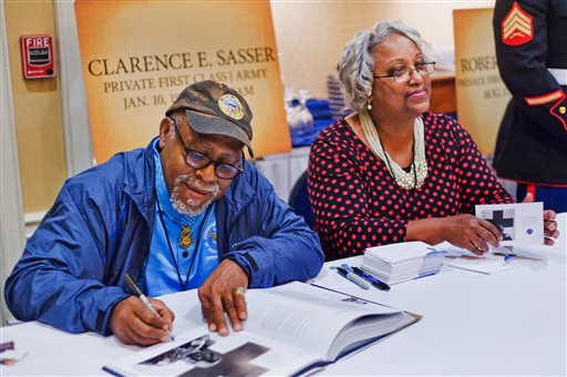Clarence E. Sasser signs autographs alongside his girlfriend, Patricia Washington. Private First Class Sasser served in Vietnam as a combat medic.