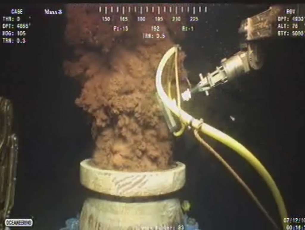 In this July 12, 2010, image from a video made available by BP PLC, oil flows out of the top of the transition spool, which was placed into the gushing wellhead and housed the containment cap, at the site of the Deepwater Horizon oil spill in the Gulf of Mexico.
