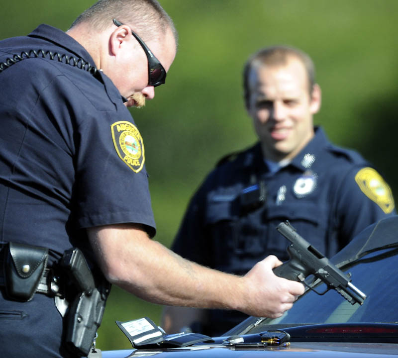 Augusta Police Department Sgt. Christopher Shaw inspects a pistol that officers briefly took from a man Tuesday following a road-rage incident in Augusta.