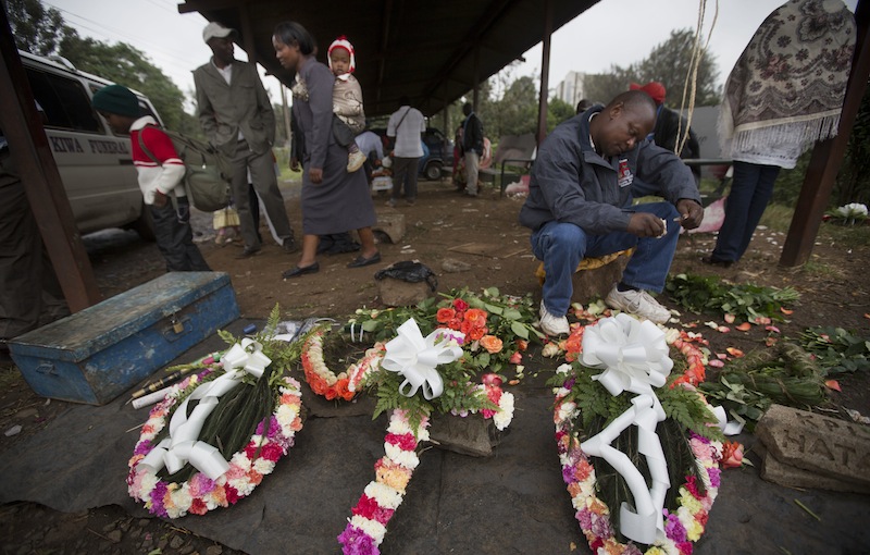A street-seller makes floral wreaths outside the mortuary in Nairobi, Kenya Wednesday, Sept. 25, 2013. Kenyan authorities prepared for the gruesome task of recovering dozens more victims than initially feared after the country's president declared an end Tuesday to the four-day siege of a Nairobi mall by al-Qaida-linked terrorists. (AP Photo/Ben Curtis)