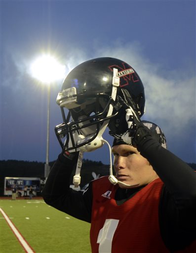 Mansfield University's Kirk Haskill is illuminated by the lights as he puts on his helmet prior to a college sprint football game against Princeton in Mansfield, Pa. on Saturday. The game marks the first time that Mansfield has held an official night football game since 1892, when Mansfield staged the first-ever night football game.